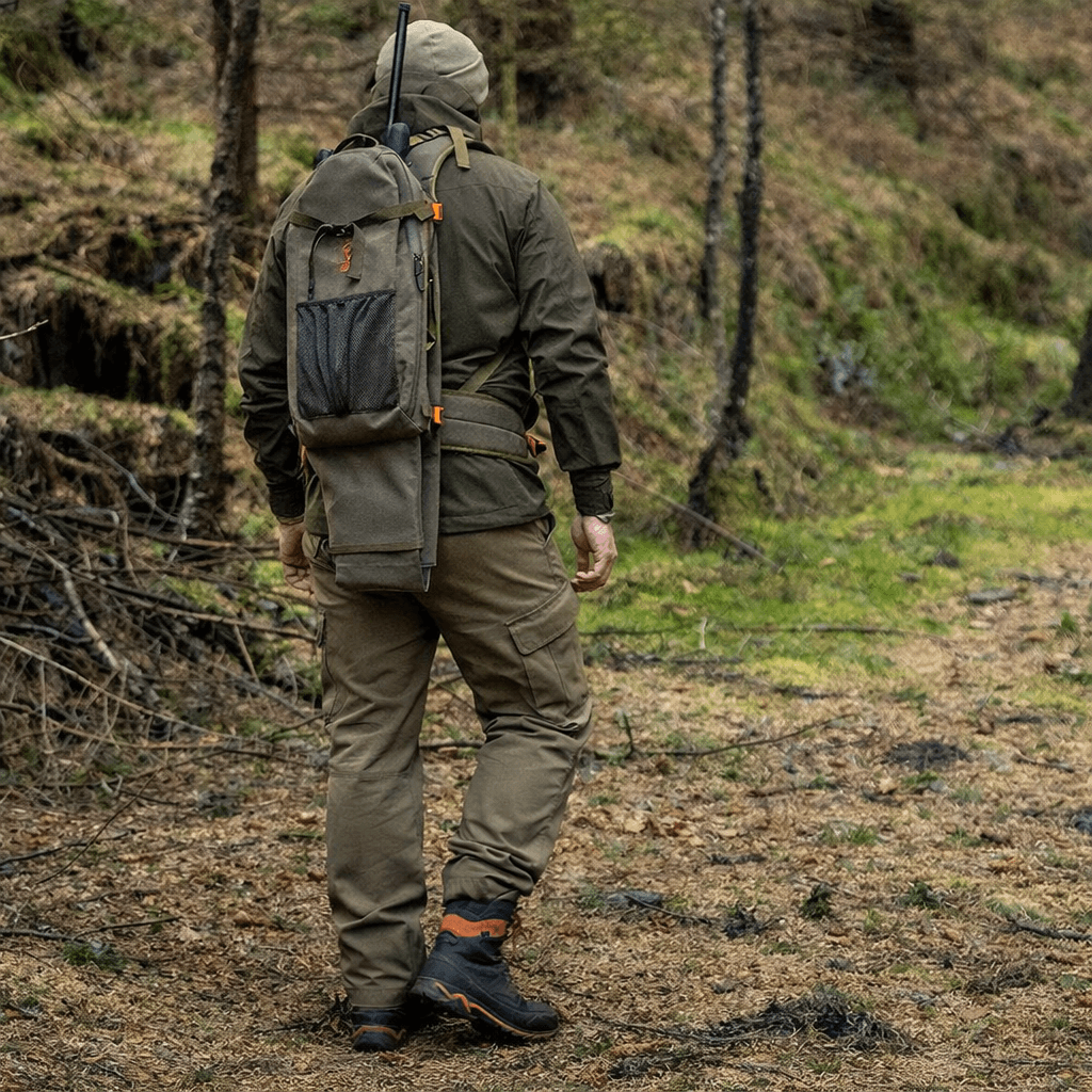 vânător cu rucsac pentru armă mergând prin pădure echipat pentru vânătoare