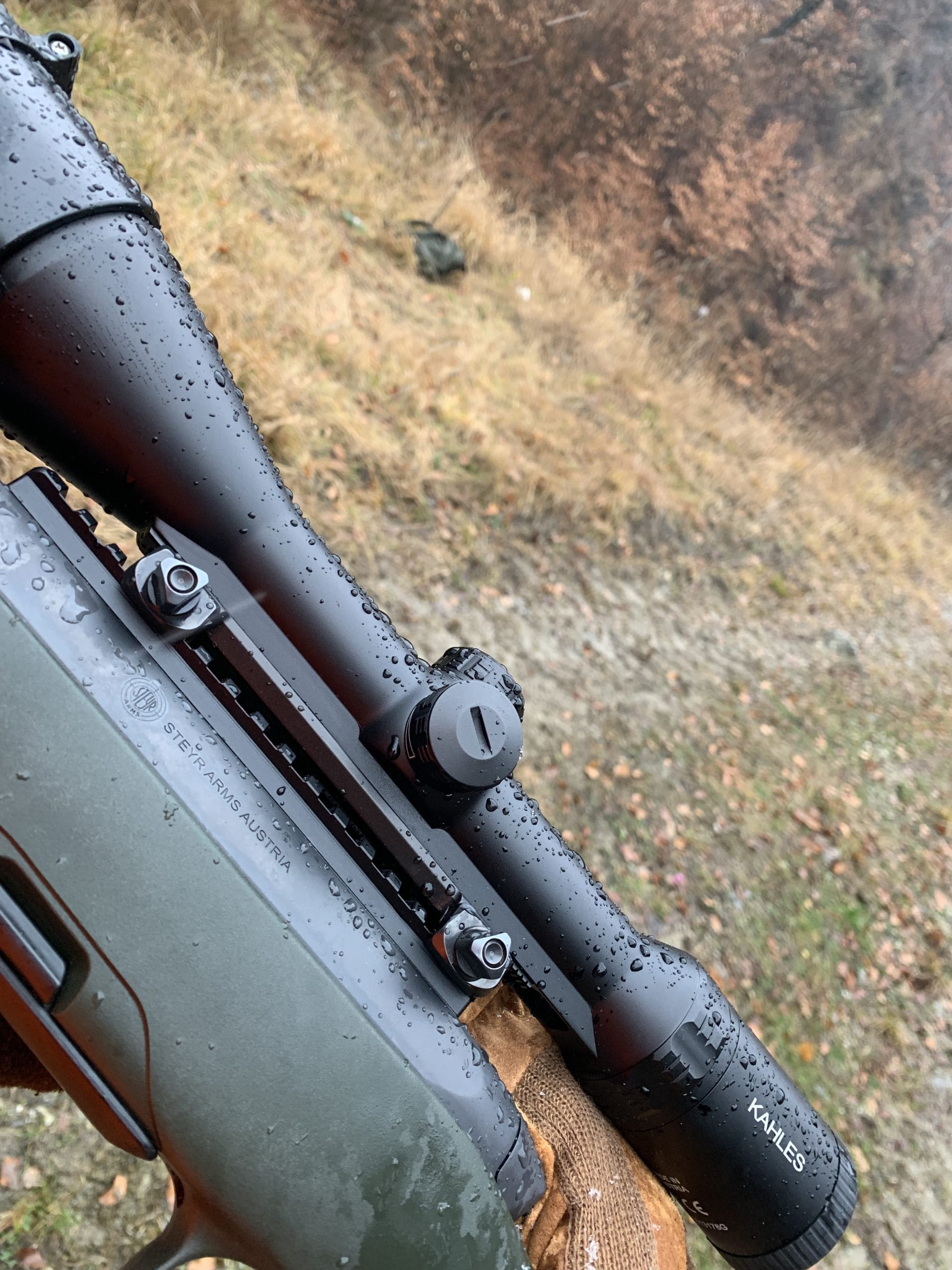 luneta Kahles Helia 2.4-12x56i cu sina montata pe carabina in teren de vanatoare